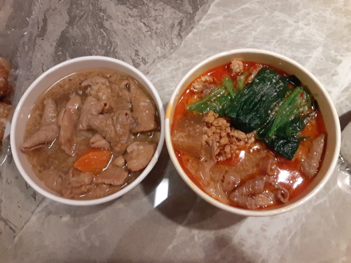 もつ煮込みと坦々もつ煮を、それぞれ白いカップに入れて並べたところ