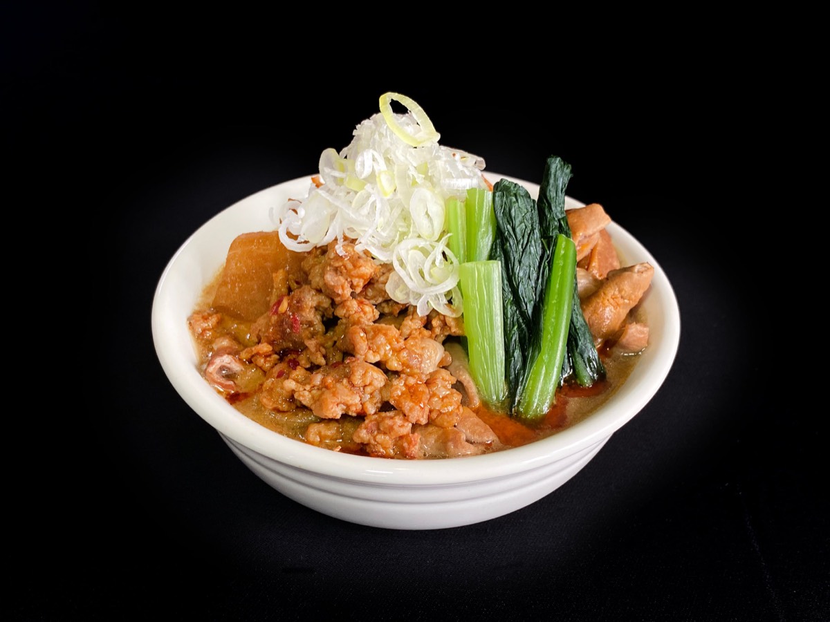 坦々もつ煮。白い丼に挽肉と青菜、白髪ねぎがのっている